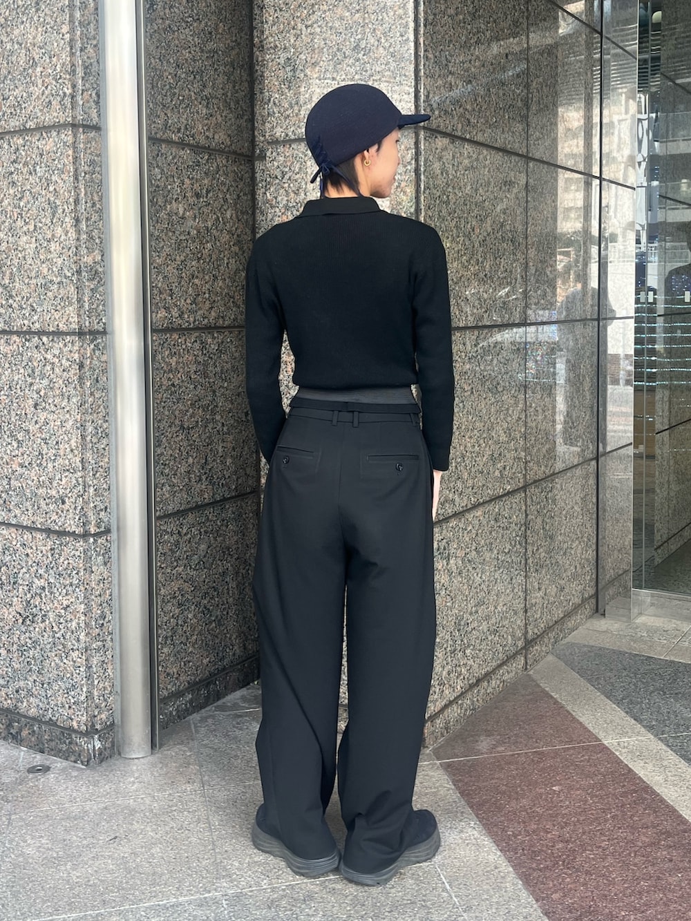 ブラック系のTシャツ/カットソー、ブラック系のスラックス、ブルー系のキャップを着用したレディースの冬コーディネートの2枚目の写真