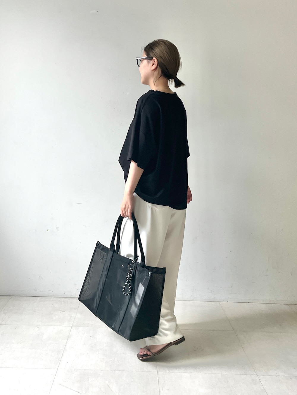 ブラック系のTシャツ/カットソー、ホワイト系のその他パンツ、ブラック系のトートバッグを着用したレディースの夏コーディネートの2枚目の写真