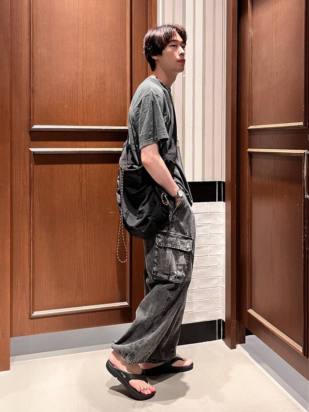 ブラック系のサンダル、グレー系のデニムパンツ、ブラック系のショルダーバッグを着用したメンズの夏コーディネートの5枚目の写真