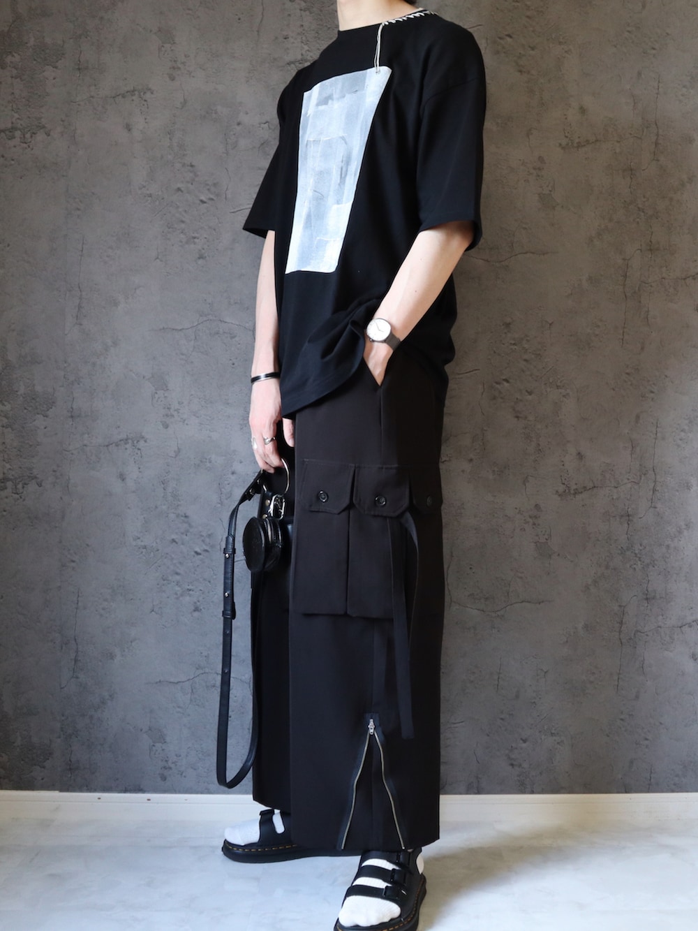 ブラック系のTシャツ/カットソー、ブラック系のカーゴパンツ、ブラック系のサンダルを着用したメンズの夏コーディネートの4枚目の写真