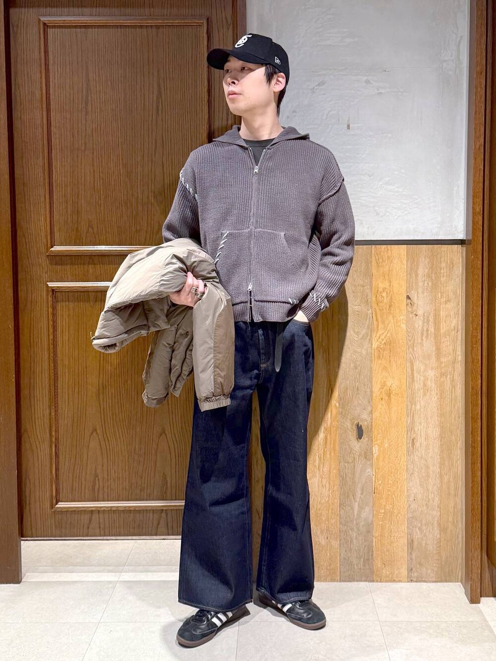 ブルー系のデニムパンツ、ブラウン系のダウンジャケット/コート、グレー系のニット/セーターを着用したメンズの冬コーディネートの2枚目の写真