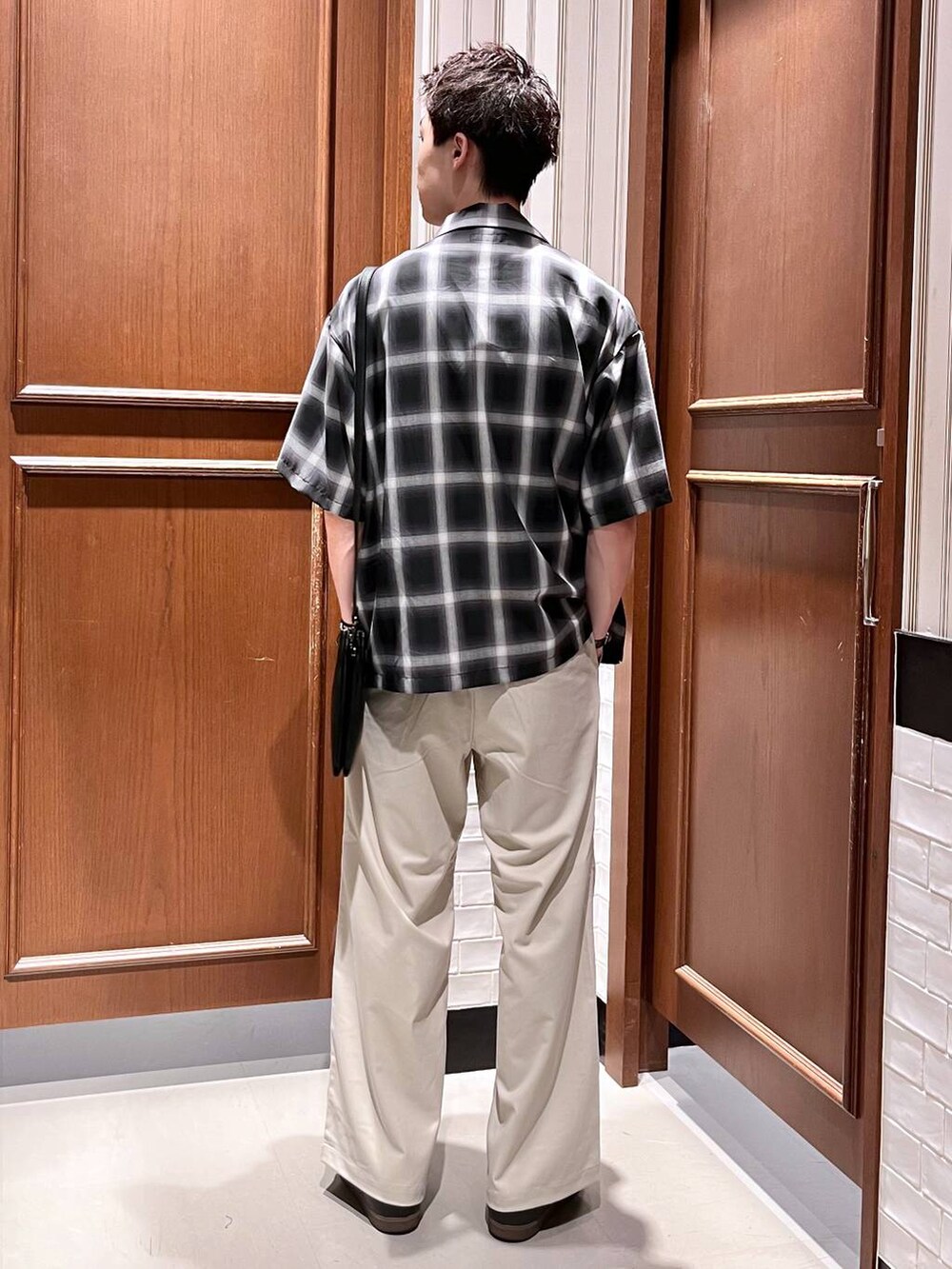 ホワイト系のスラックス、ブラック系のショルダーバッグ、ブラック系のシャツ/ブラウスを着用したメンズの夏コーディネートの4枚目の写真