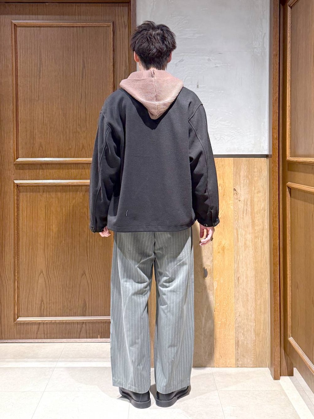 ブラック系のブルゾン、ブラウン系のニット/セーター、グレー系のスラックスを着用したメンズの冬コーディネートの5枚目の写真