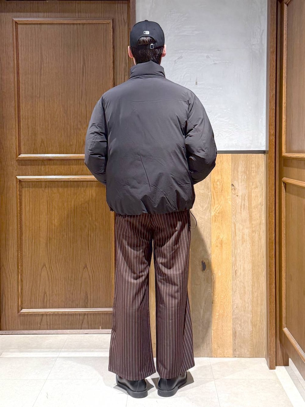 ブラック系のダウンジャケット/コート、グレー系のニット/セーター、ブラウン系のスラックスを着用したメンズの冬コーディネートの5枚目の写真