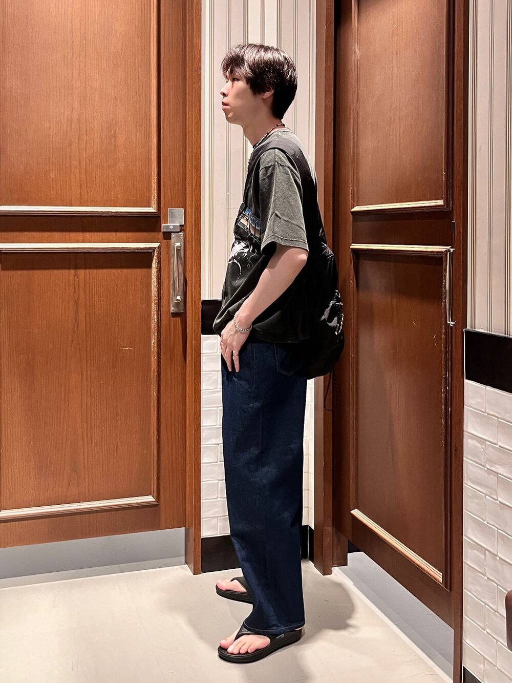 ブラック系のサンダル、ブルー系のデニムパンツ、ブラック系のショルダーバッグを着用したメンズの夏コーディネートの4枚目の写真