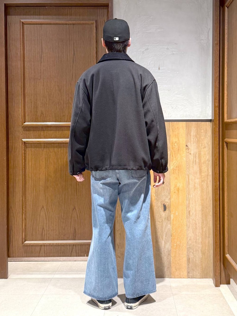 ブラック系のブルゾン、ホワイト系のニット/セーター、ブルー系のデニムパンツを着用したメンズの冬コーディネートの5枚目の写真