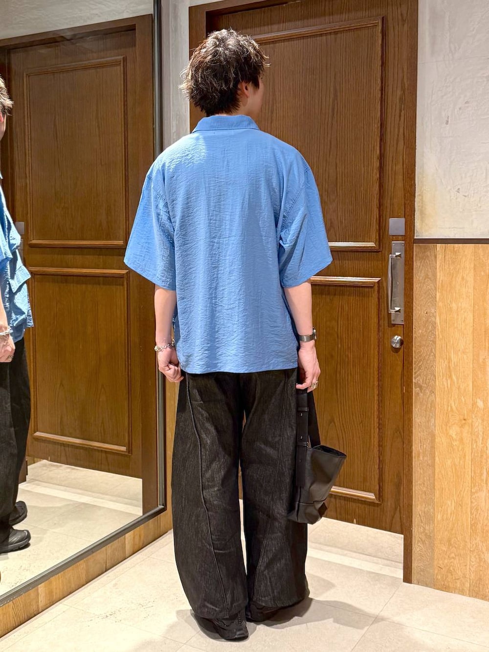 ブラック系のハンドバッグ、ブラック系のデニムパンツ、ブルー系のシャツ/ブラウスを着用したメンズの春コーディネートの4枚目の写真
