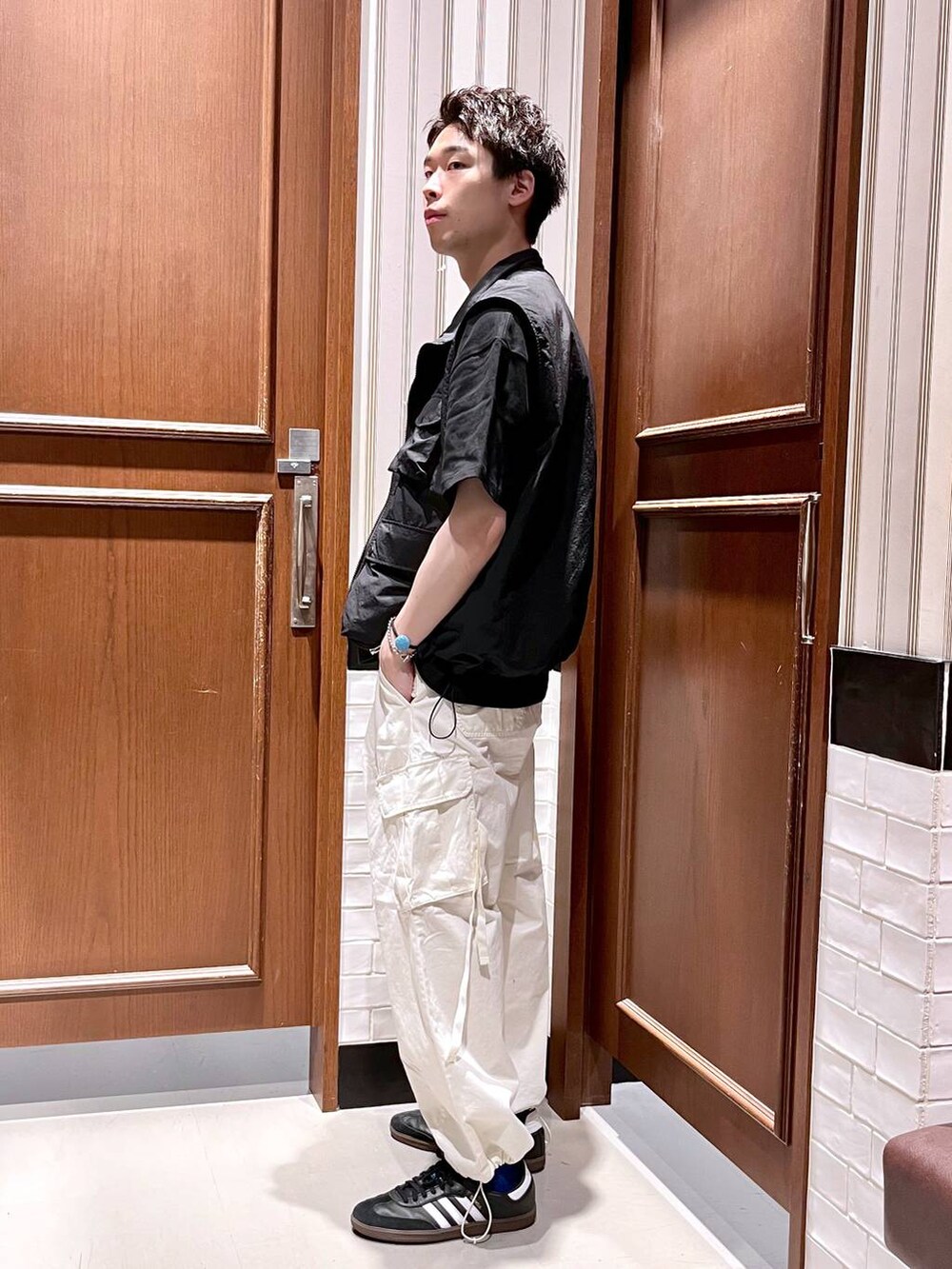 ホワイト系のカーゴパンツ、ブラック系のベスト、ブラック系のTシャツ/カットソーを着用したメンズの夏コーディネートの4枚目の写真