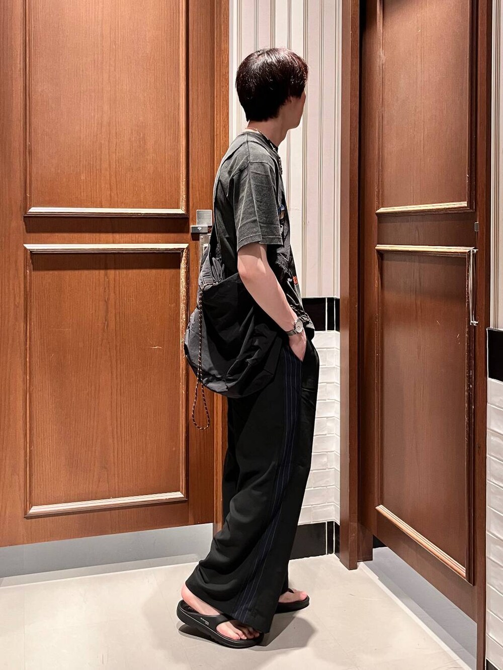ブラック系のサンダル、ブラック系のショルダーバッグ、ブラック系のスラックスを着用したメンズの夏コーディネートの3枚目の写真
