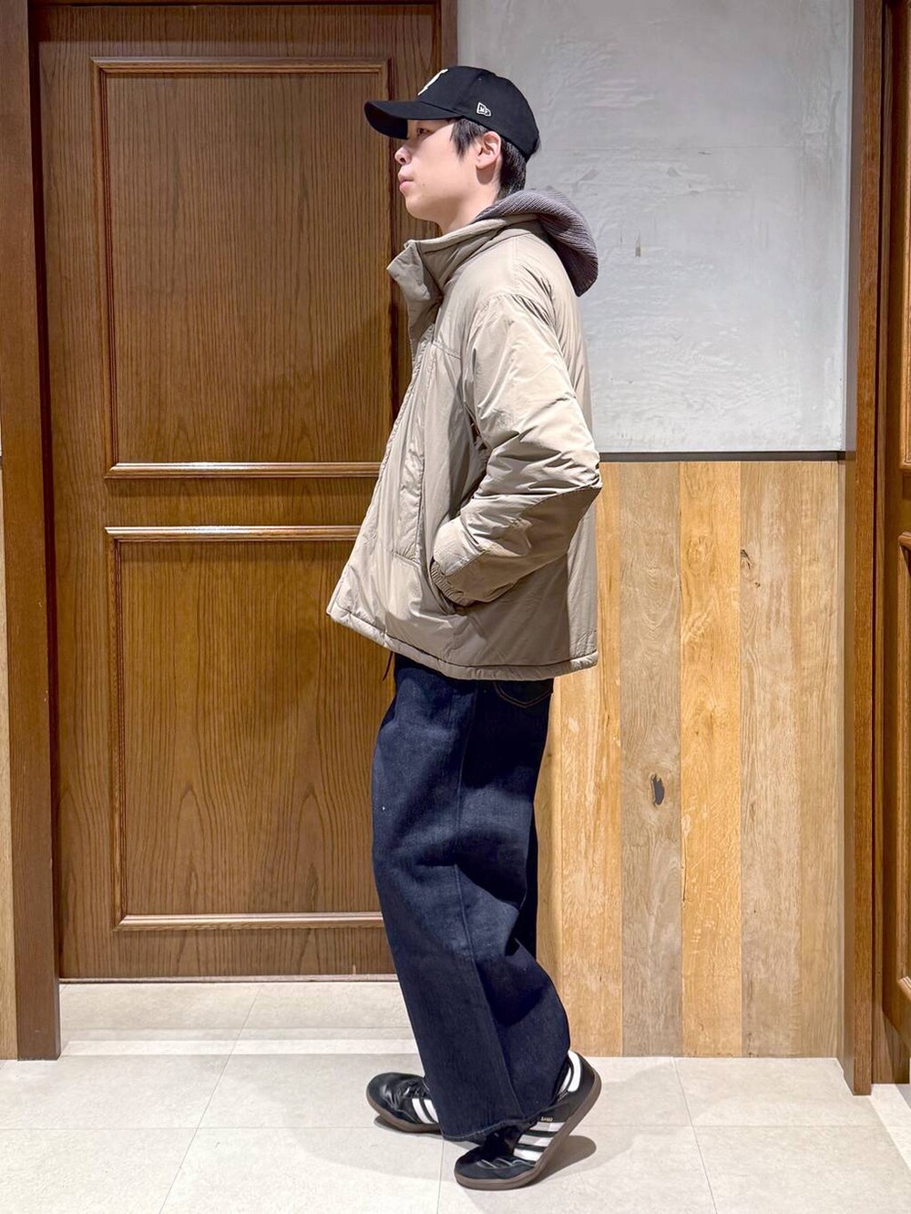 ブルー系のデニムパンツ、ブラウン系のダウンジャケット/コート、グレー系のニット/セーターを着用したメンズの冬コーディネートの3枚目の写真