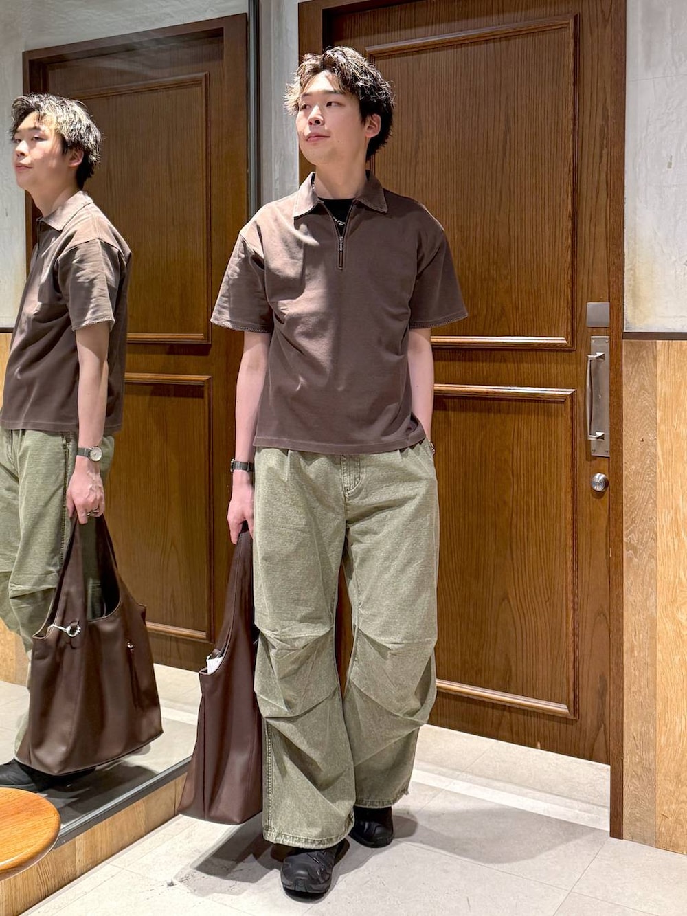 ブラウン系のトートバッグ、グリーン系のカーゴパンツ、ブラウン系のTシャツ/カットソーを着用したメンズの春コーディネートの2枚目の写真