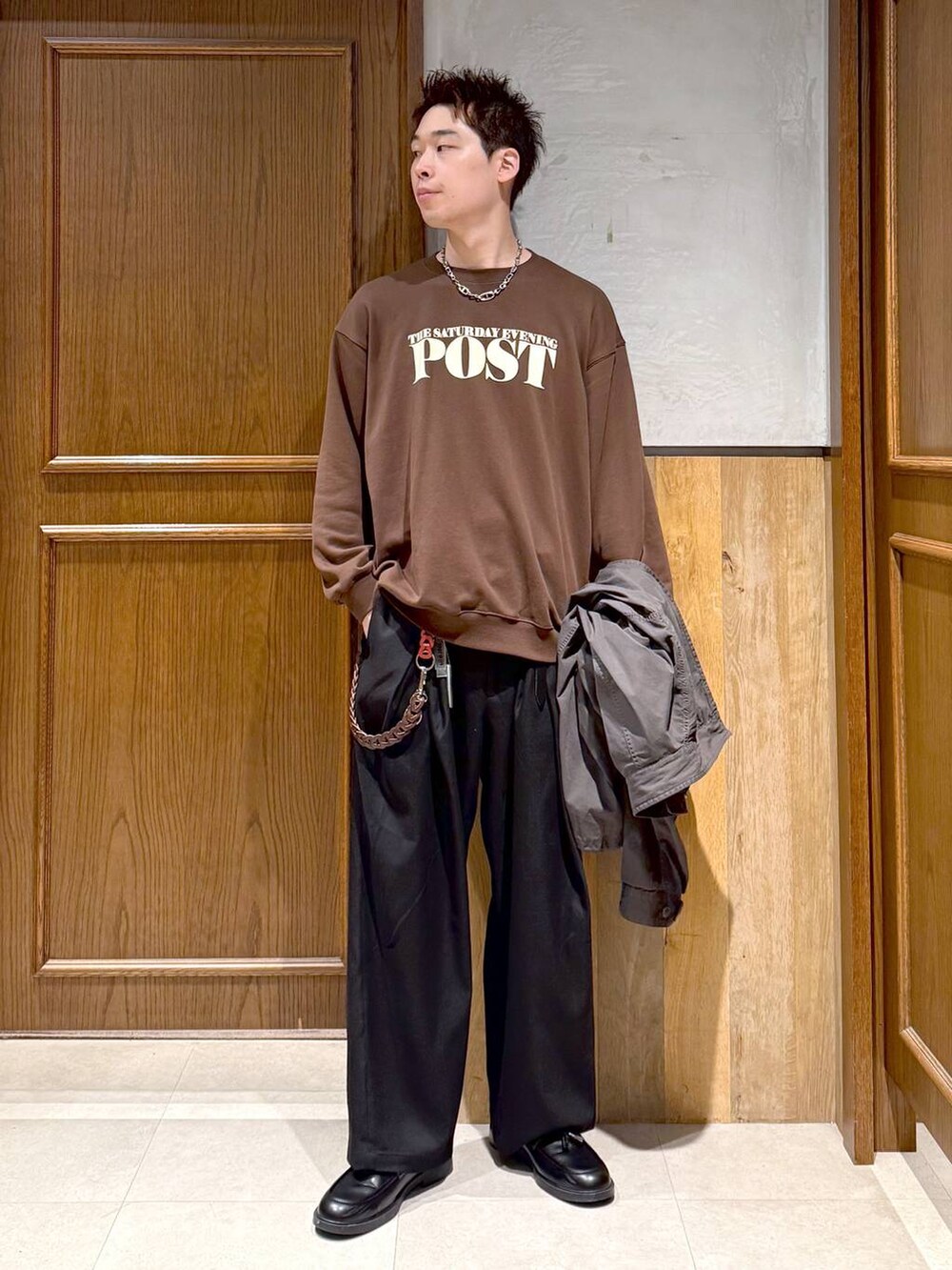 グレー系のモッズコート、ブラック系のスラックス、ブラウン系のスウェットを着用したメンズの秋コーディネートの2枚目の写真