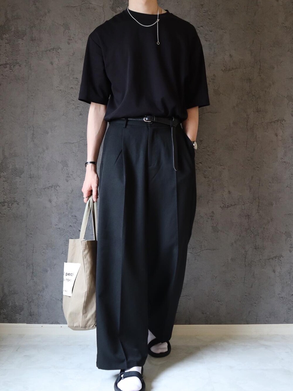 ブラック系のスラックス、ベージュ系のトートバッグ、ブラック系のサンダルを着用したメンズの夏コーディネートの2枚目の写真