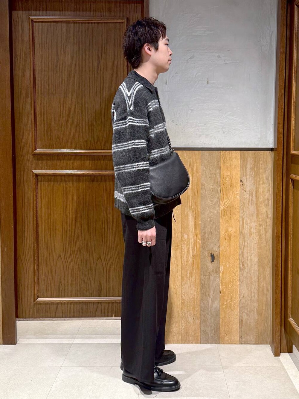 ブラック系のショルダーバッグ、ブラック系のポロシャツ、ブラック系のスラックスを着用したメンズの冬コーディネートの6枚目の写真