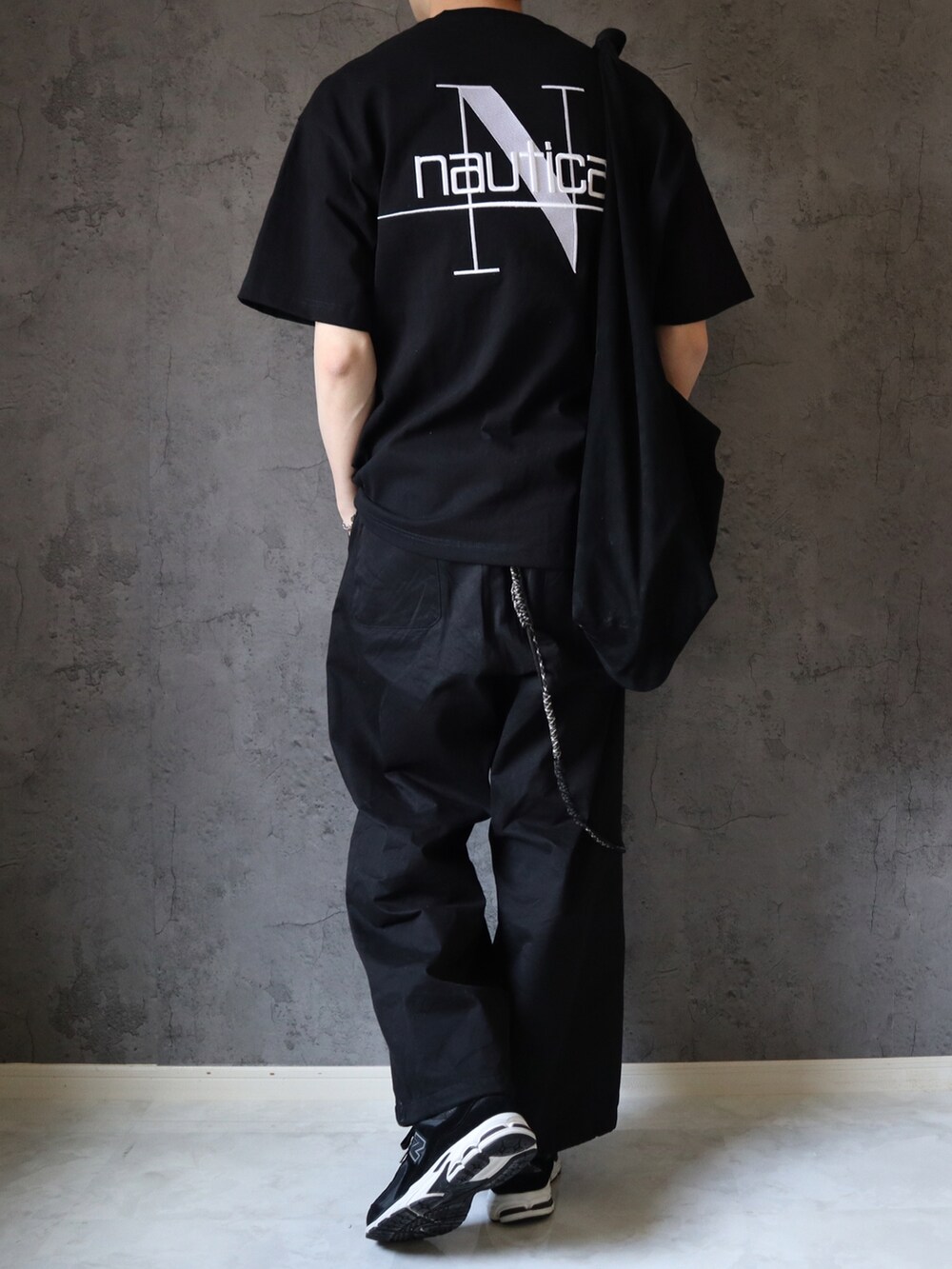 ブラック系のTシャツ/カットソー、ブラック系のチノパンツ、ブラック系のスニーカーを着用したメンズの春コーディネートの3枚目の写真