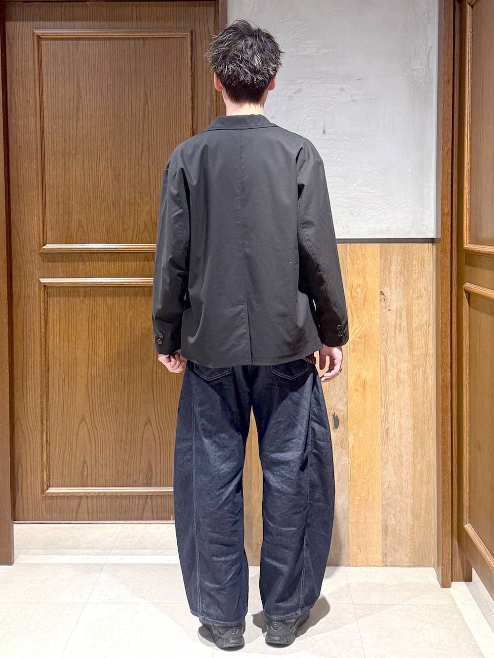 ブラック系のテーラードジャケット、ホワイト系のTシャツ/カットソー、ブルー系のデニムパンツを着用したメンズの春コーディネートの4枚目の写真