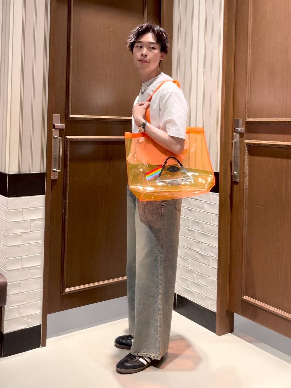 オレンジ系のショルダーバッグ、ブルー系のデニムパンツ、ホワイト系のTシャツ/カットソーを着用したメンズの夏コーディネートの2枚目の写真