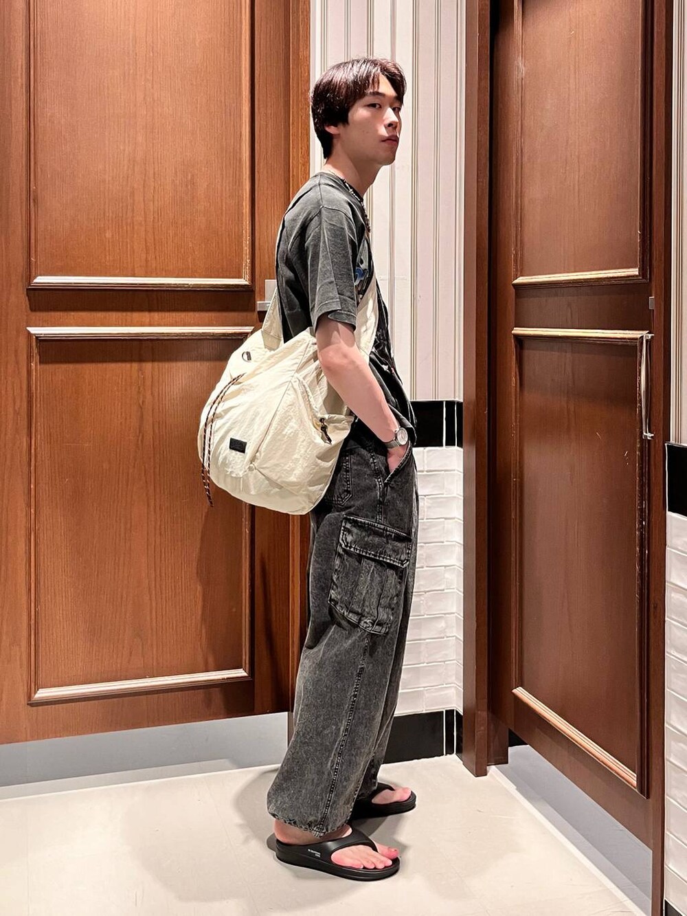 ブラック系のサンダル、グレー系のデニムパンツ、ホワイト系のショルダーバッグを着用したメンズの夏コーディネートの4枚目の写真