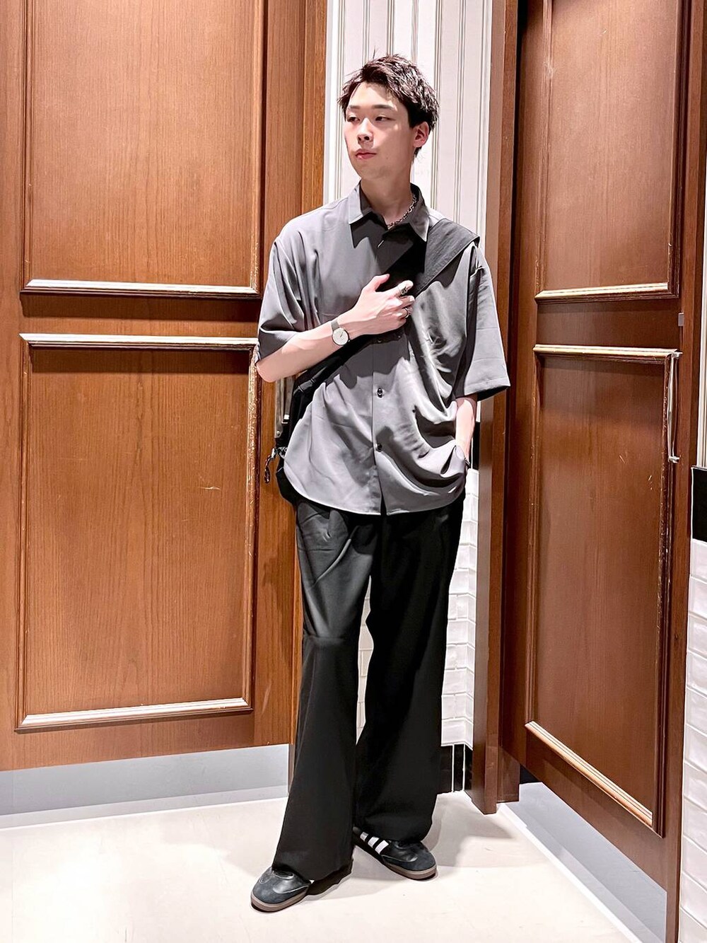 ブラック系のスラックス、グレー系のシャツ/ブラウス、ブラック系のショルダーバッグを着用したメンズの夏コーディネートの2枚目の写真