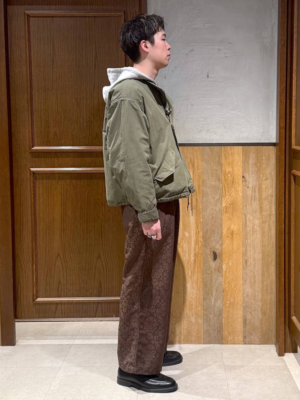 グリーン系のモッズコート、イエロー系のスラックス、グレー系のパーカーを着用したメンズの冬コーディネートの6枚目の写真