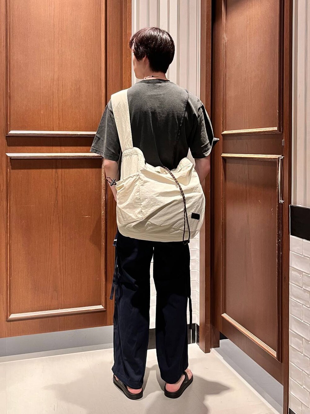 ブラック系のサンダル、ブルー系のカーゴパンツ、ホワイト系のショルダーバッグを着用したメンズの夏コーディネートの4枚目の写真