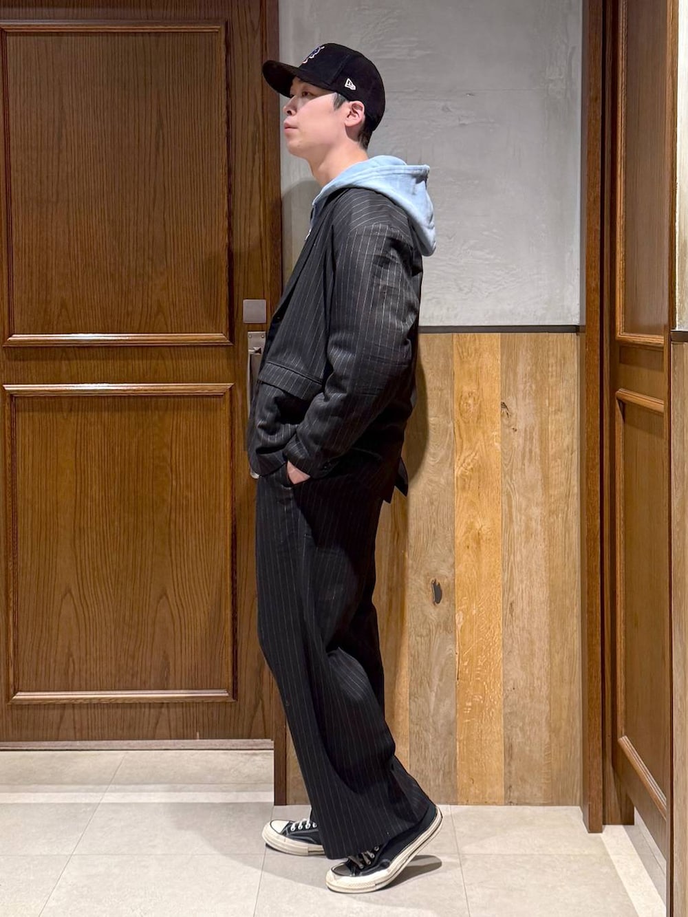 ブラック系のスラックス、ブラック系のテーラードジャケット、ブルー系のパーカーを着用したメンズの冬コーディネートの4枚目の写真