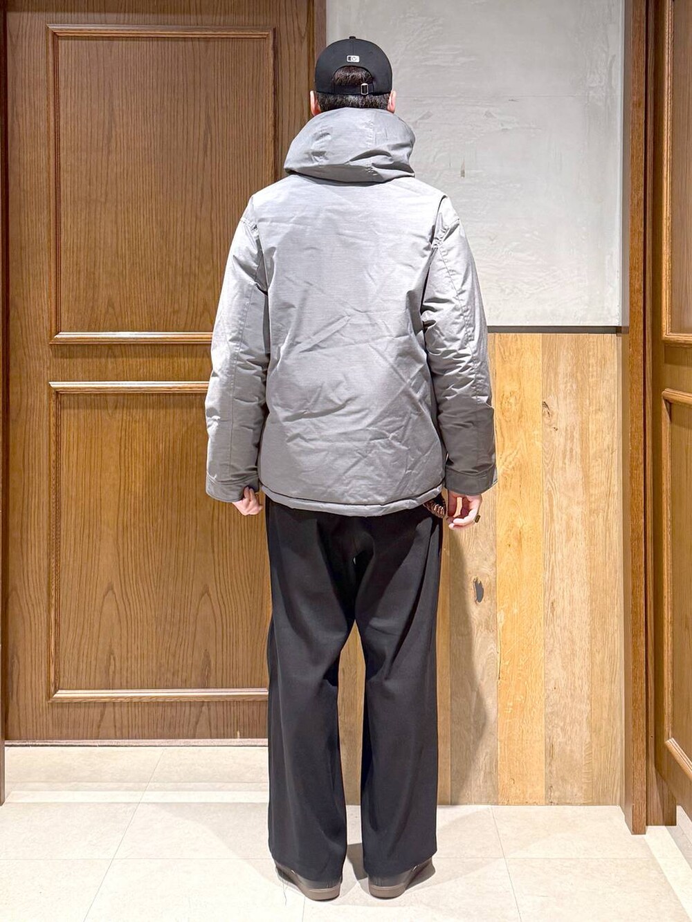 グレー系のダウンジャケット/コート、ブラック系のスラックス、レッド系のスウェットを着用したメンズの冬コーディネートの6枚目の写真