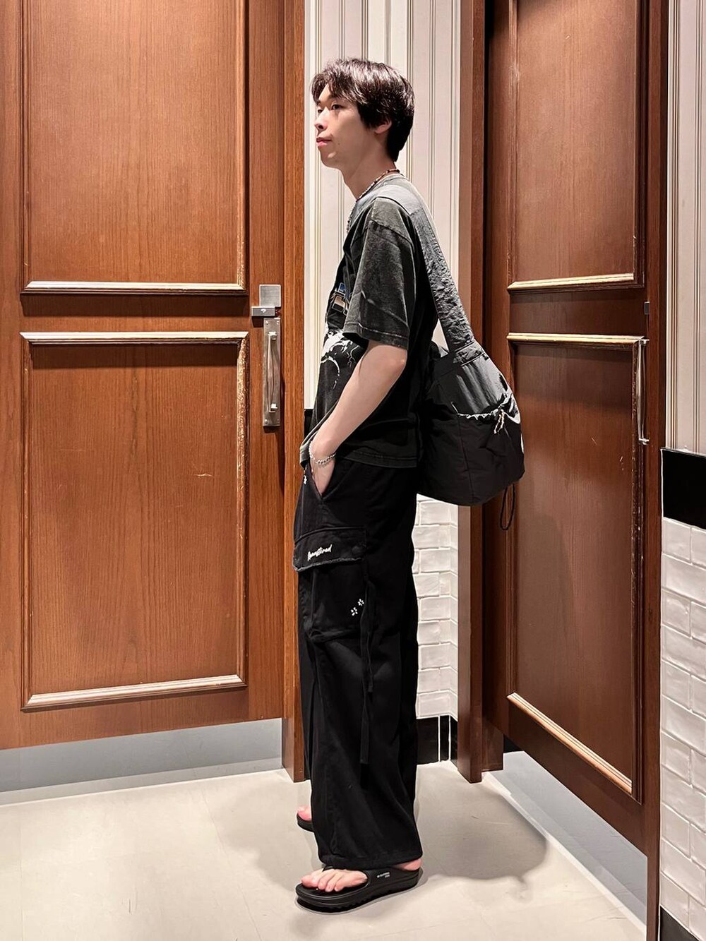 ブラック系のサンダル、ブラック系のカーゴパンツ、グレー系のショルダーバッグを着用したメンズの夏コーディネートの3枚目の写真