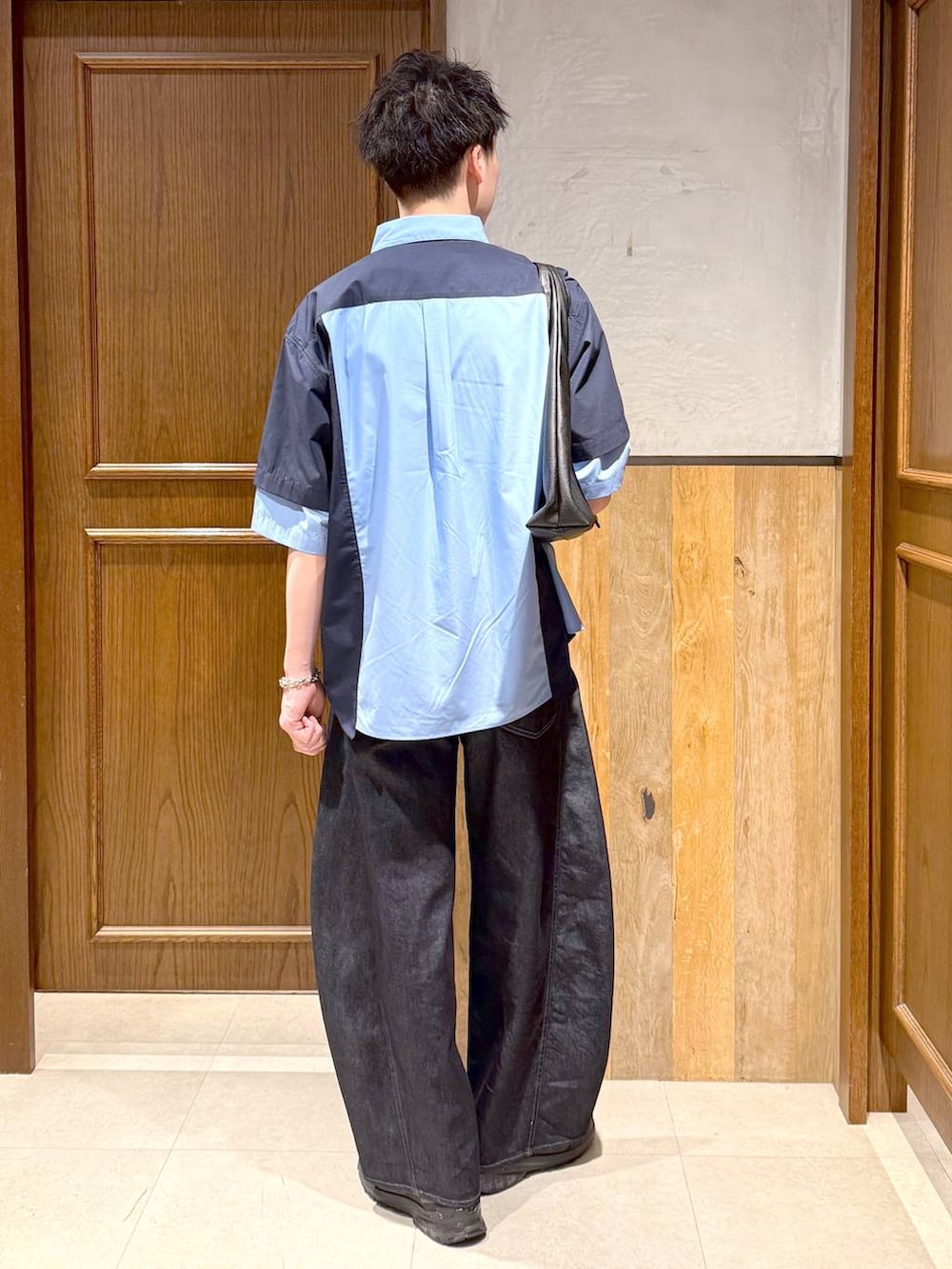 ブラック系のトートバッグ、ブルー系のデニムパンツ、ブルー系のシャツ/ブラウスを着用したメンズの春コーディネートの4枚目の写真