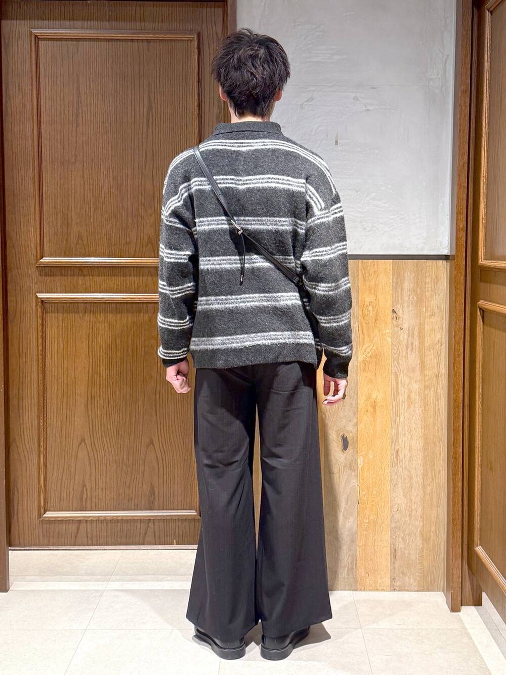 ブラック系のショルダーバッグ、ブラック系のポロシャツ、ブラック系のスラックスを着用したメンズの冬コーディネートの5枚目の写真