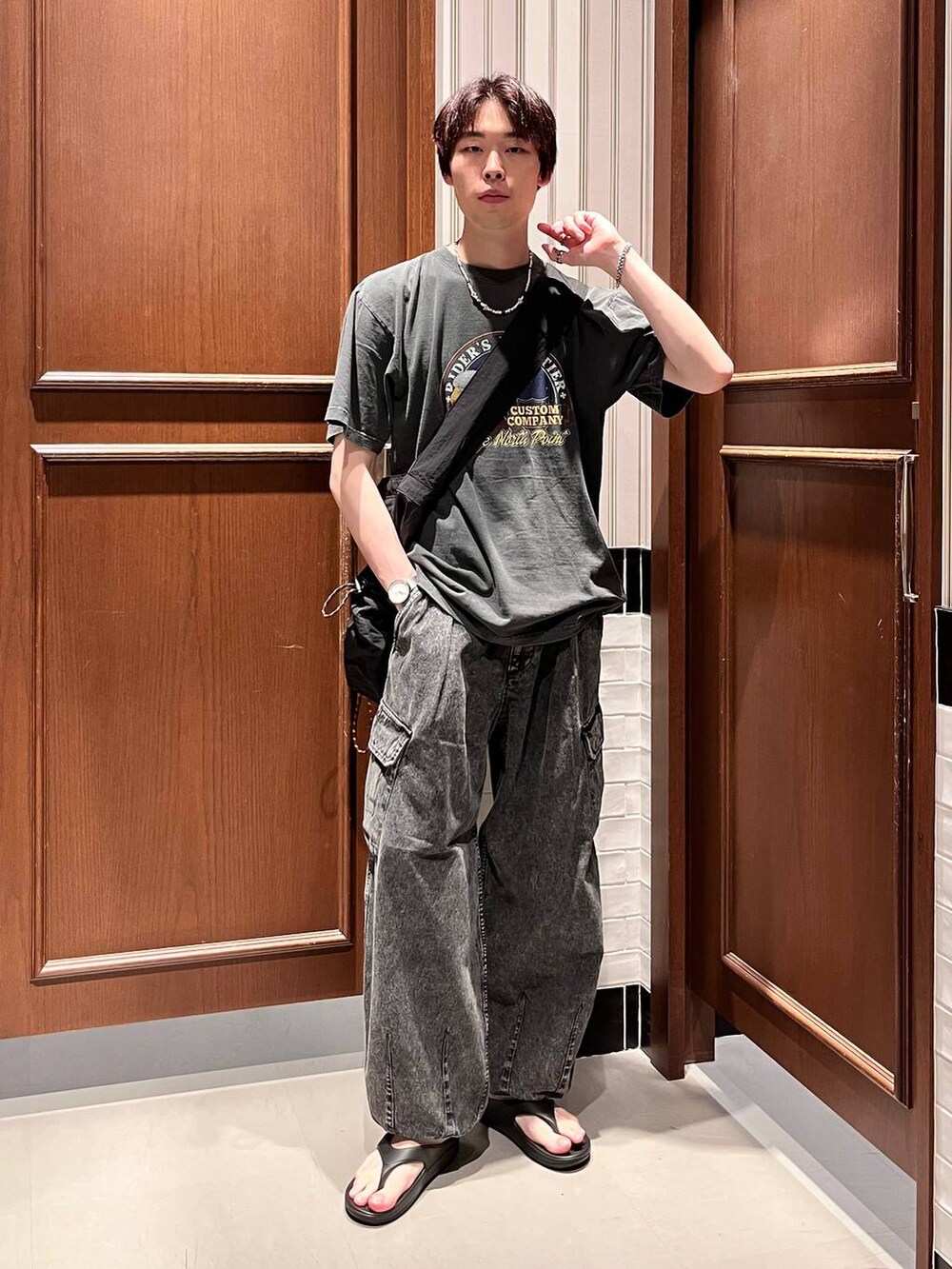 ブラック系のサンダル、グレー系のデニムパンツ、ブラック系のショルダーバッグを着用したメンズの夏コーディネートの6枚目の写真