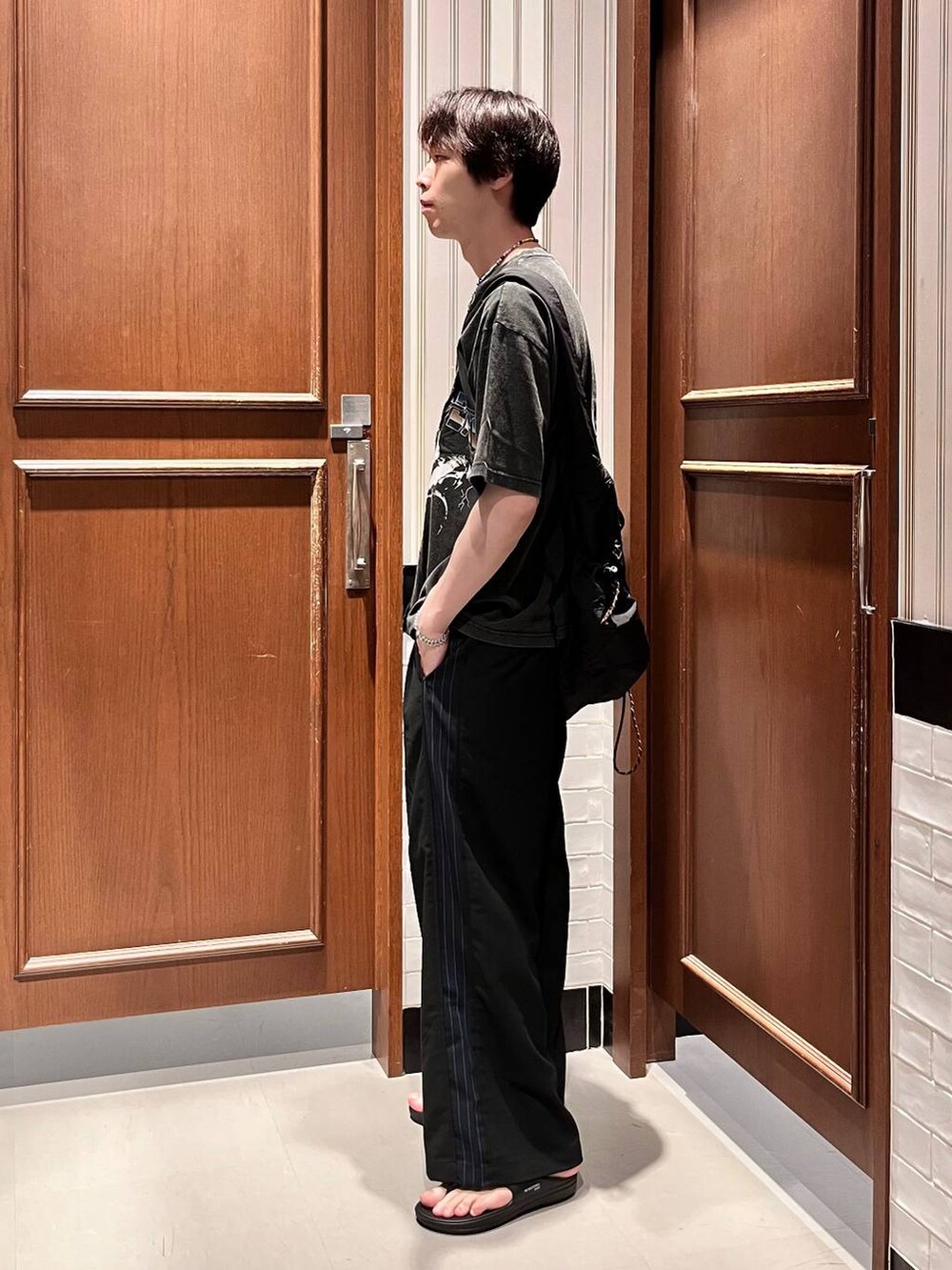 ブラック系のサンダル、ブラック系のショルダーバッグ、ブラック系のスラックスを着用したメンズの夏コーディネートの5枚目の写真