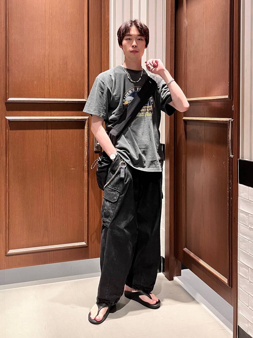 ブラック系のサンダル、グレー系のデニムパンツ、ブラック系のショルダーバッグを着用したメンズの夏コーディネートの2枚目の写真