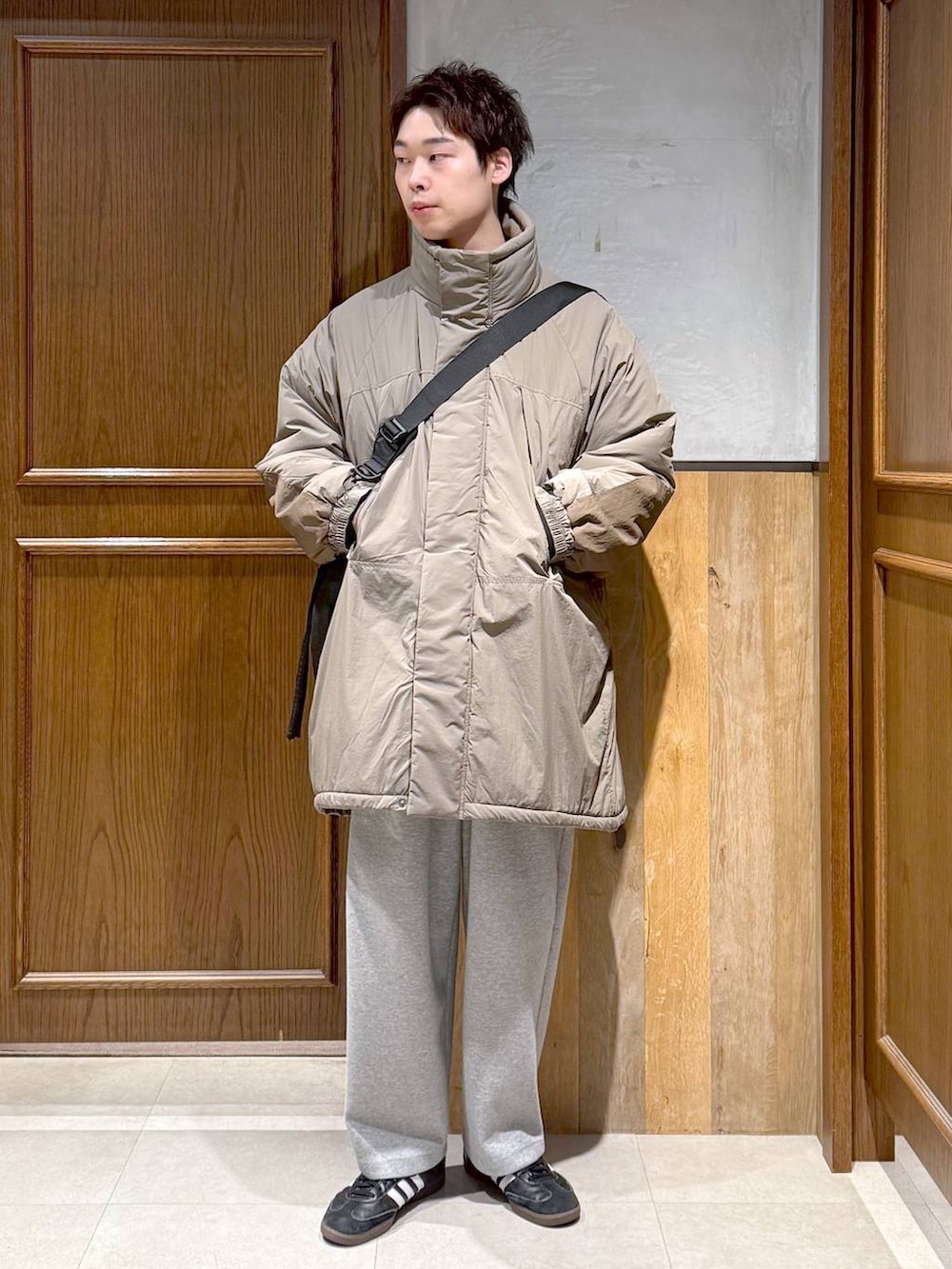 グリーン系のダウンジャケット/コート、ブラック系のポロシャツ、グレー系のスウェットパンツを着用したメンズの秋コーディネートの4枚目の写真