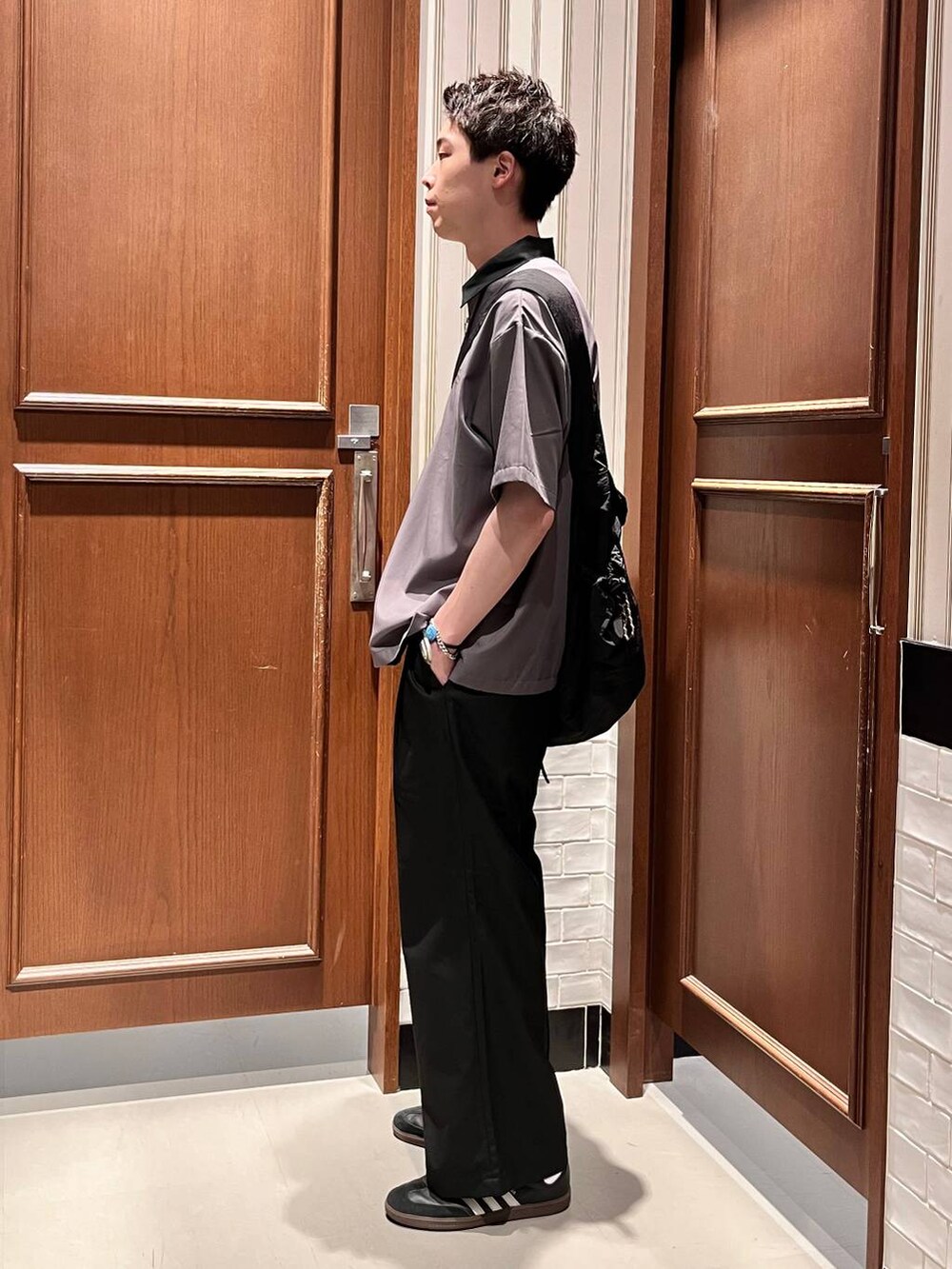 ブラック系のスラックス、ブラック系のショルダーバッグ、グレー系のシャツ/ブラウスを着用したメンズの夏コーディネートの3枚目の写真