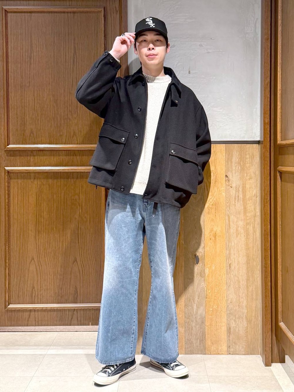 ブラック系のブルゾン、ホワイト系のニット/セーター、ブルー系のデニムパンツを着用したメンズの冬コーディネートの3枚目の写真