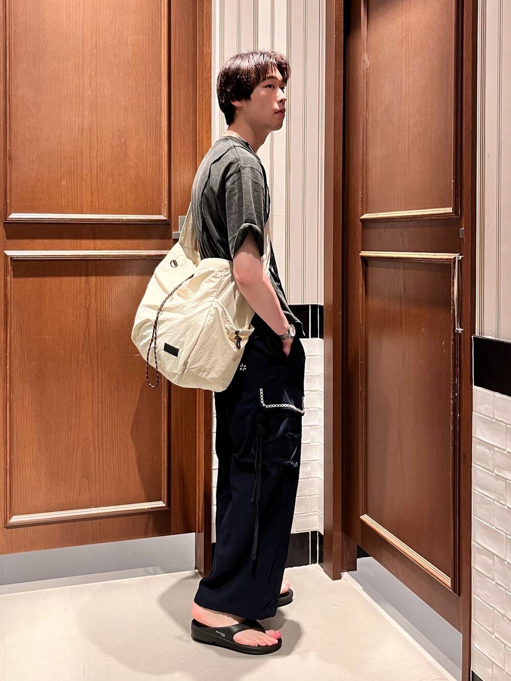 ブラック系のサンダル、ブルー系のカーゴパンツ、ホワイト系のショルダーバッグを着用したメンズの夏コーディネートの3枚目の写真