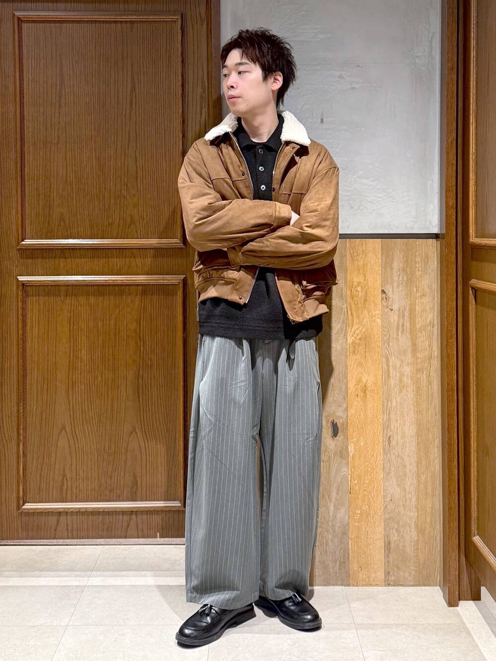 イエロー系のブルゾン、ブラック系のポロシャツ、グレー系のスラックスを着用したメンズの冬コーディネートの3枚目の写真