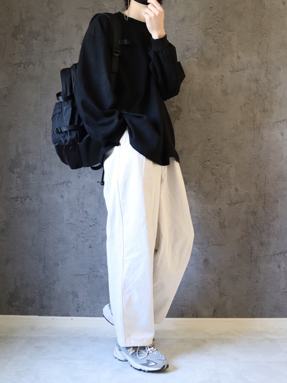 ブラック系のスウェット、ホワイト系のスラックス、グレー系のスニーカーを着用したメンズの春コーディネートの2枚目の写真