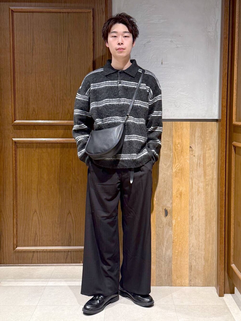 ブラック系のショルダーバッグ、ブラック系のポロシャツ、ブラック系のスラックスを着用したメンズの冬コーディネートの7枚目の写真