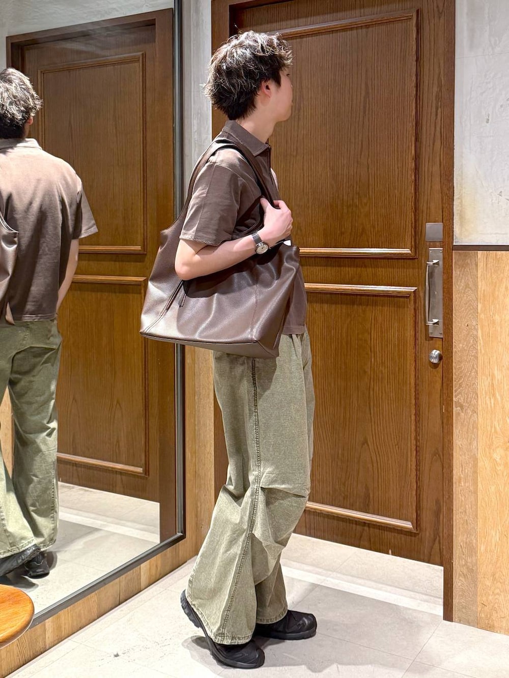 ブラウン系のトートバッグ、グリーン系のカーゴパンツ、ブラウン系のTシャツ/カットソーを着用したメンズの春コーディネートの5枚目の写真