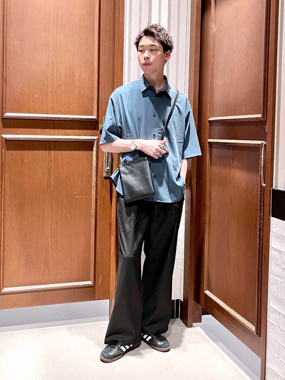 ブラック系のスラックス、ブラック系のショルダーバッグ、ブルー系のシャツ/ブラウスを着用したメンズの夏コーディネートの2枚目の写真