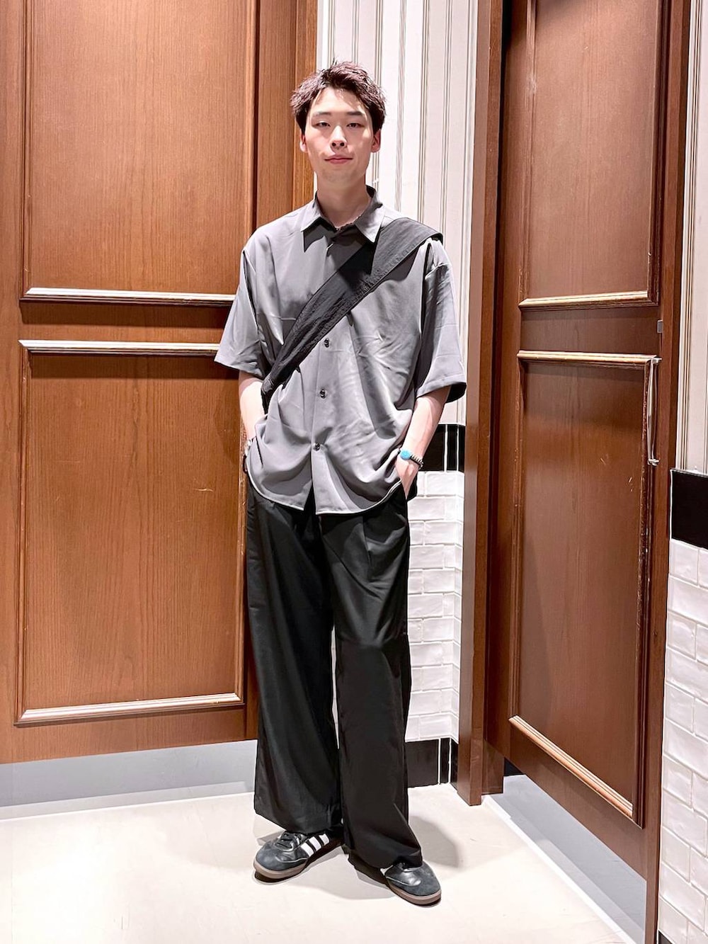 ブラック系のスラックス、グレー系のシャツ/ブラウス、ブラック系のショルダーバッグを着用したメンズの夏コーディネートの3枚目の写真