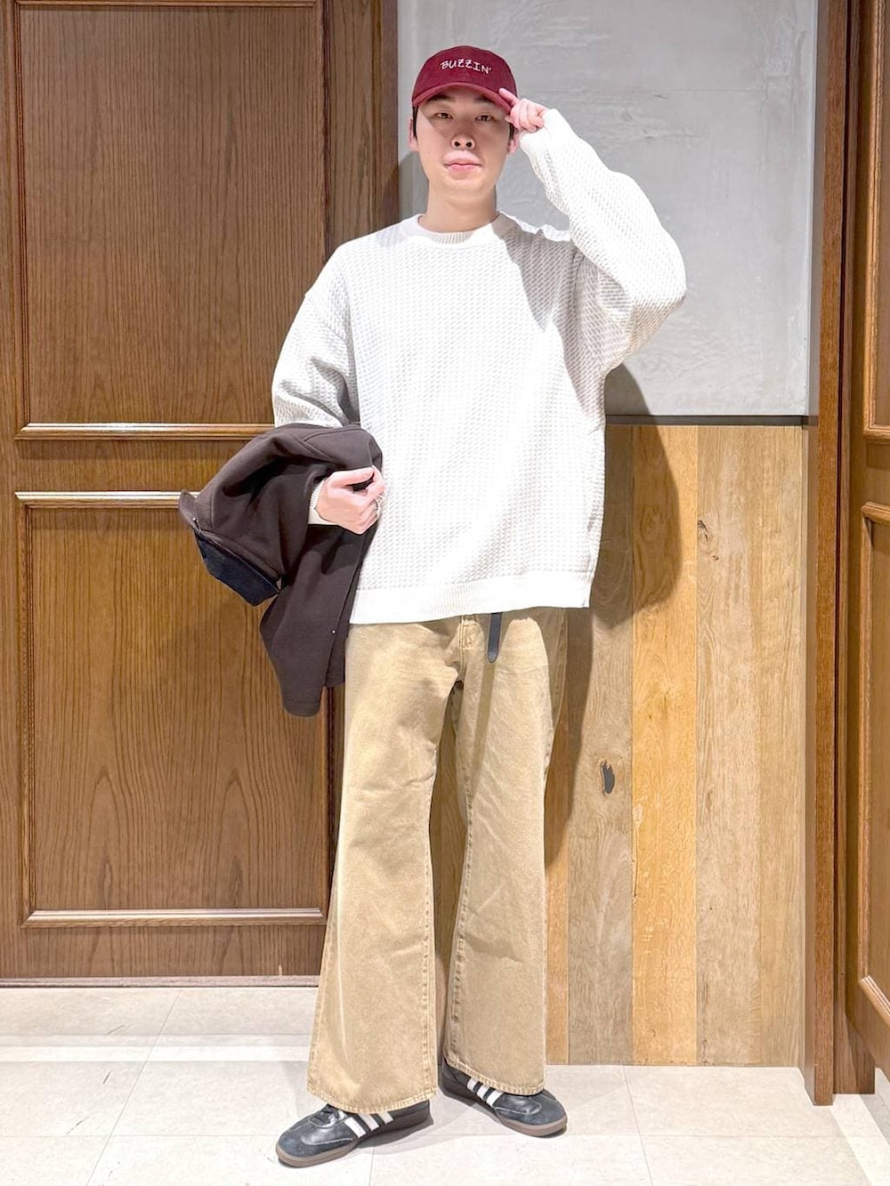 ブラウン系のブルゾン、ホワイト系のニット/セーター、ベージュ系のデニムパンツを着用したメンズの冬コーディネートの2枚目の写真
