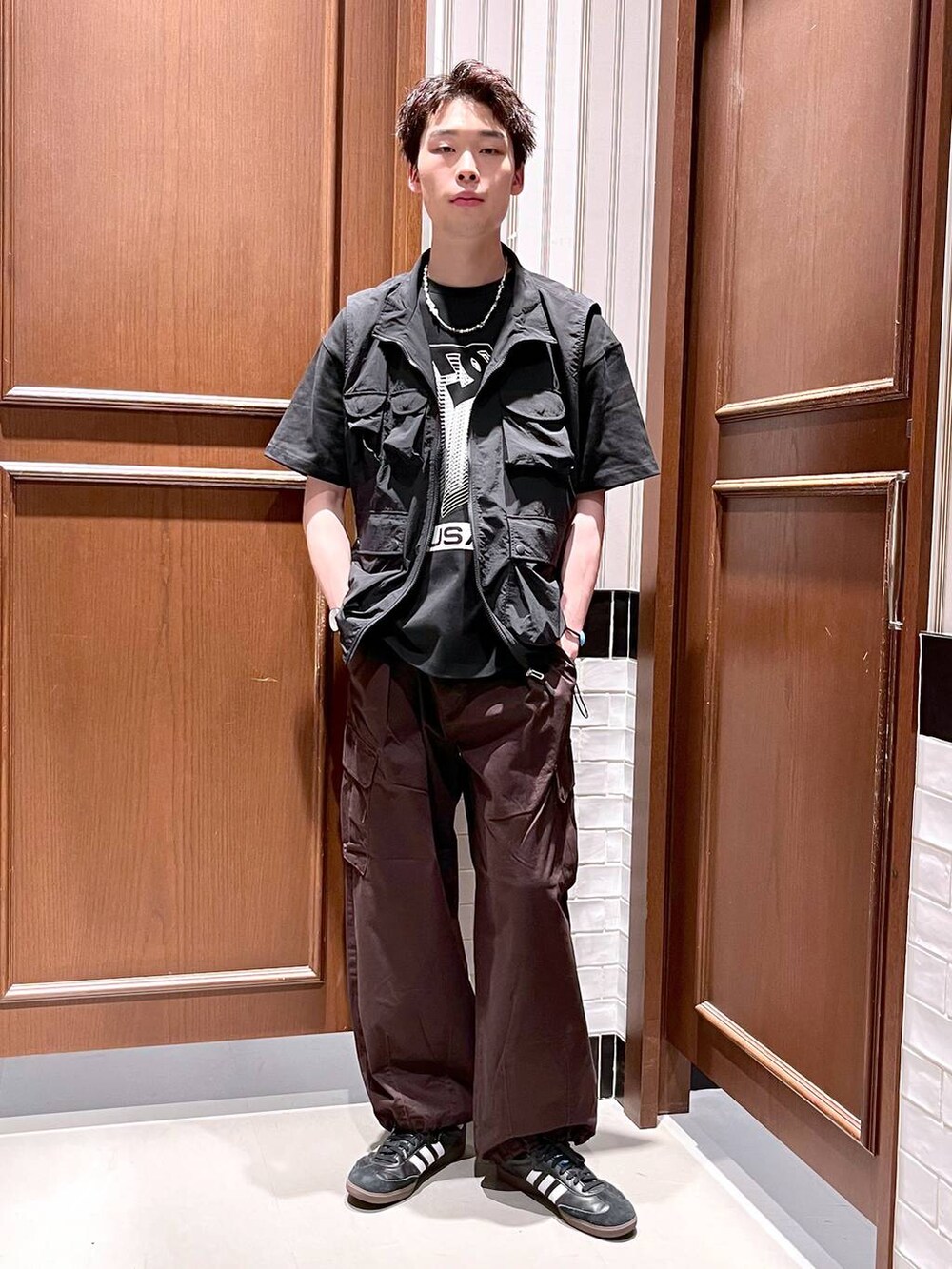 ブラウン系のカーゴパンツ、ブラック系のベスト、ブラック系のTシャツ/カットソーを着用したメンズの夏コーディネートの2枚目の写真