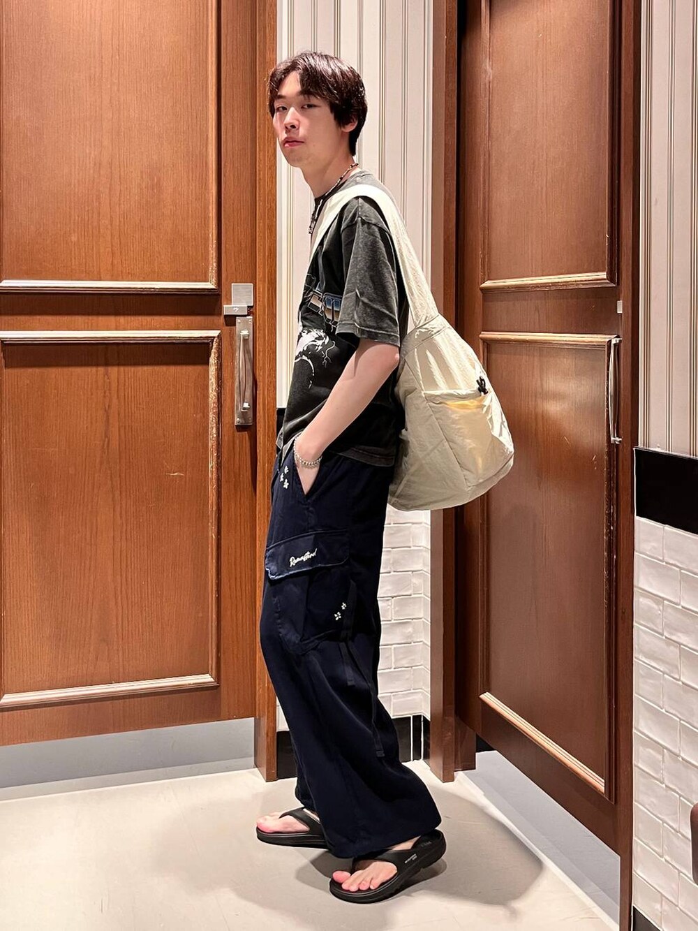 ブラック系のサンダル、ブルー系のカーゴパンツ、ホワイト系のショルダーバッグを着用したメンズの夏コーディネートの5枚目の写真