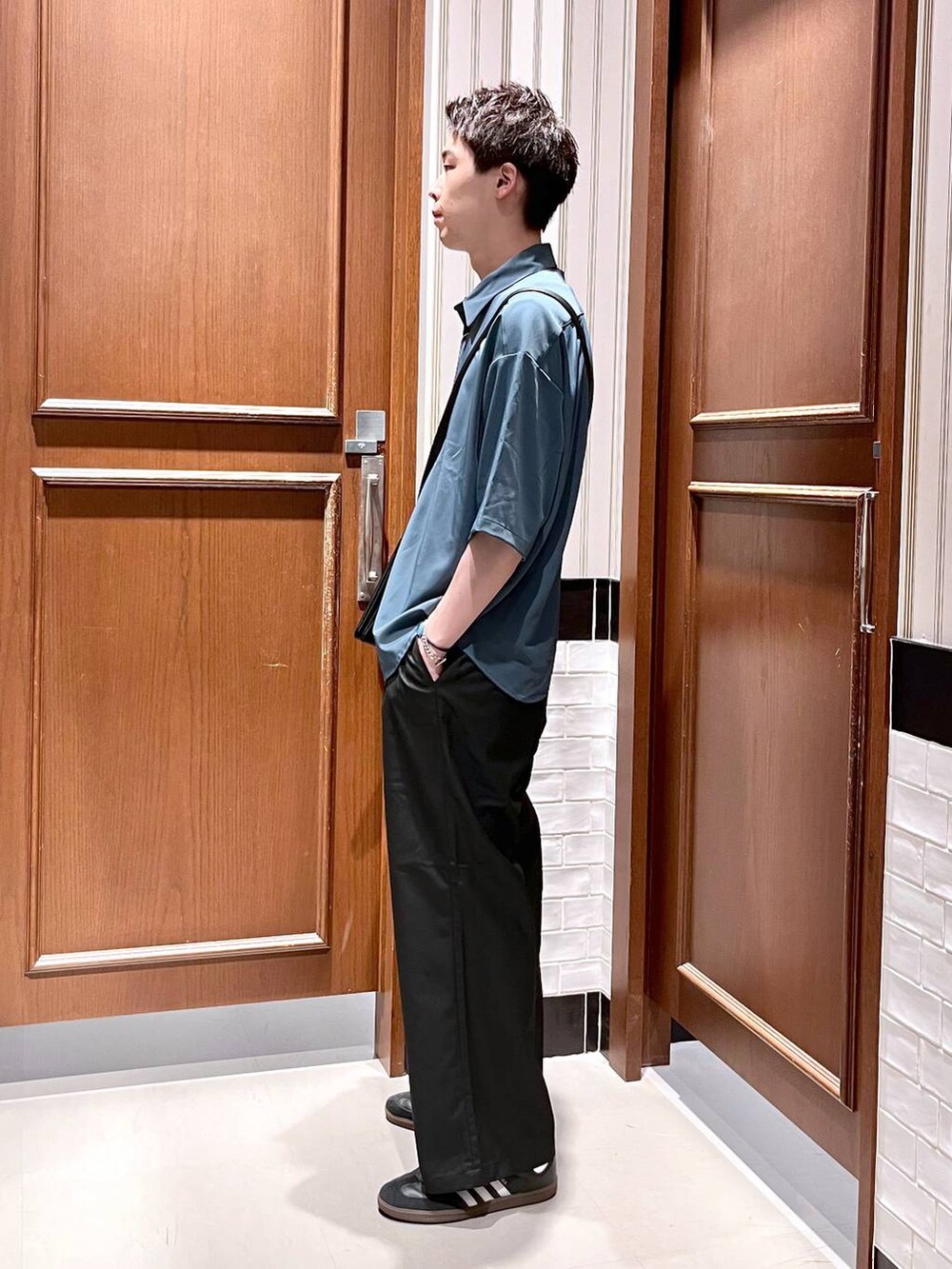 ブラック系のスラックス、ブラック系のショルダーバッグ、ブルー系のシャツ/ブラウスを着用したメンズの夏コーディネートの3枚目の写真