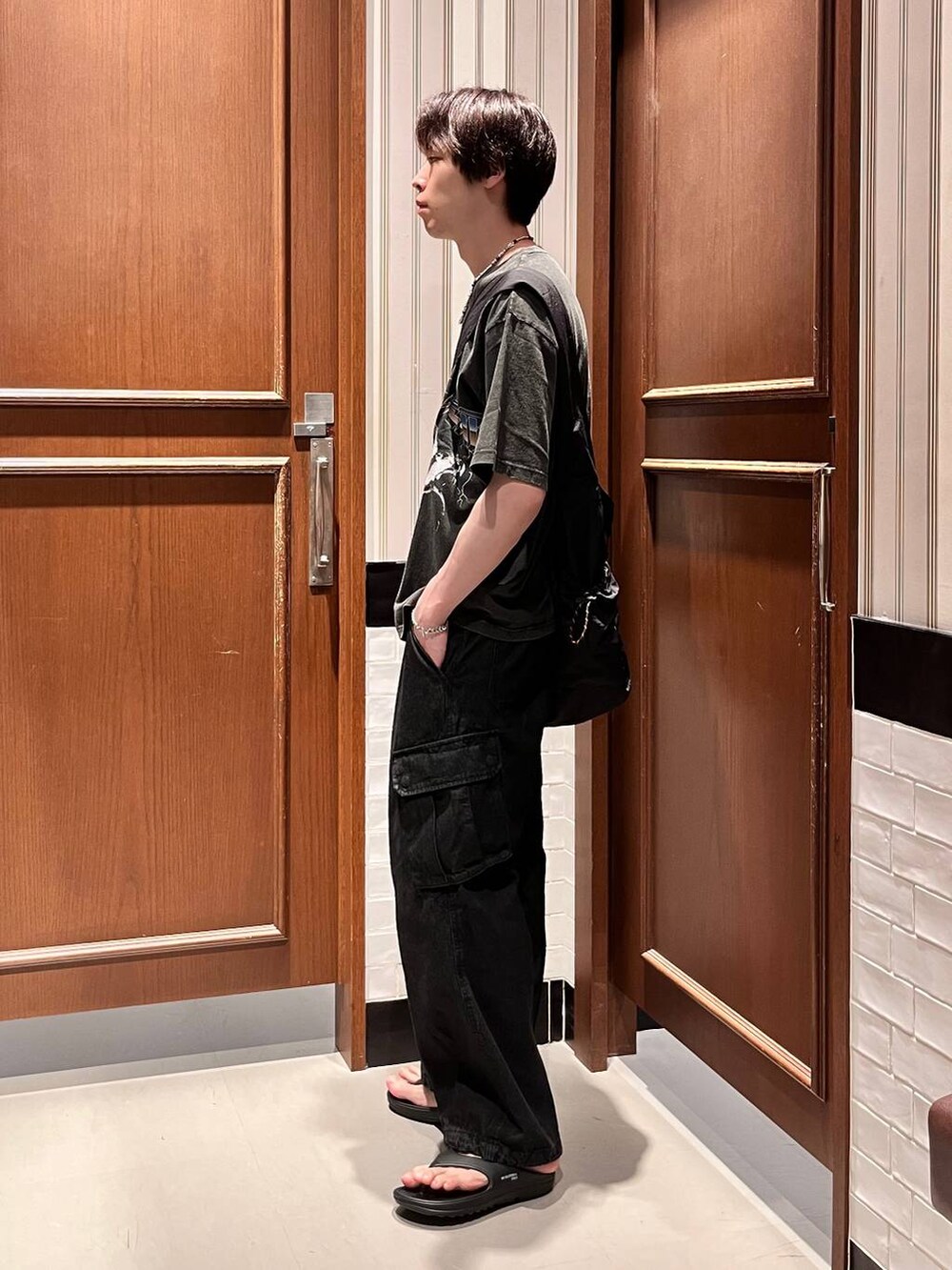 グレー系のデニムパンツ、ブラック系のショルダーバッグ、ブラック系のサンダルを着用したメンズの夏コーディネートの3枚目の写真