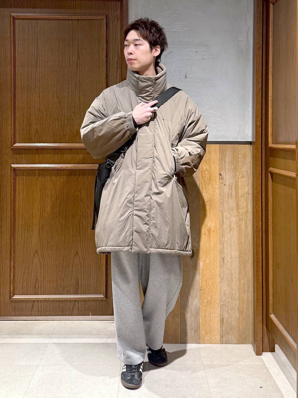 グリーン系のダウンジャケット/コート、ブラック系のポロシャツ、グレー系のスウェットパンツを着用したメンズの秋コーディネートの3枚目の写真