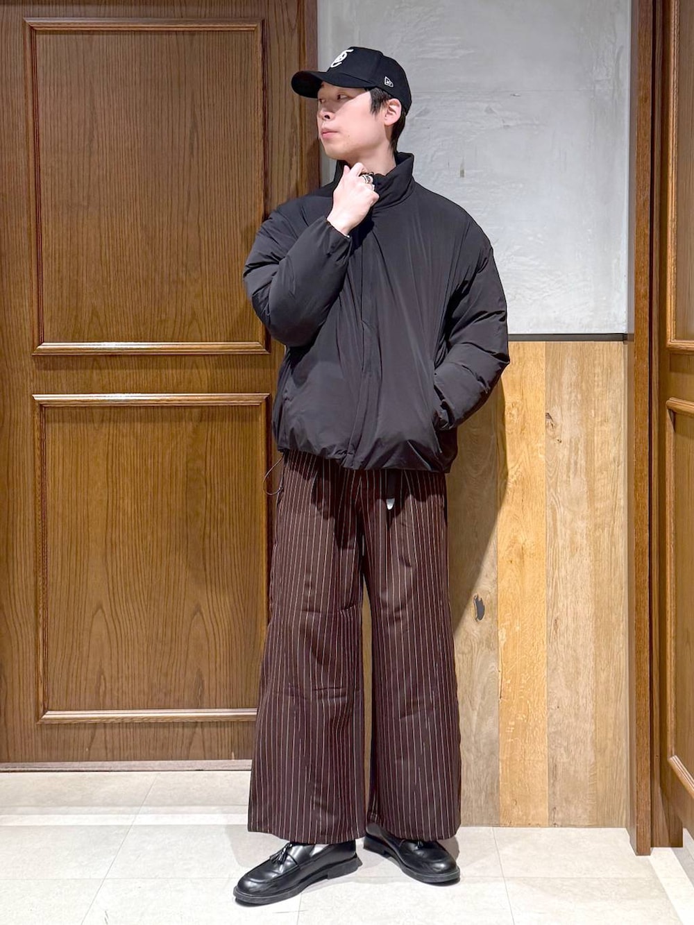 ブラック系のダウンジャケット/コート、グレー系のニット/セーター、ブラウン系のスラックスを着用したメンズの冬コーディネートの7枚目の写真